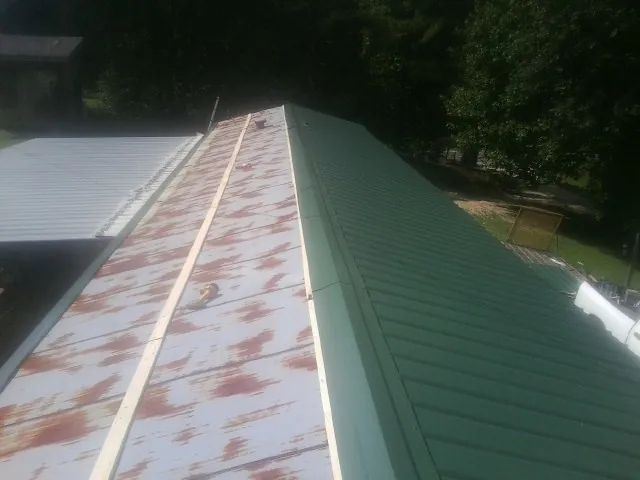 Old rusted panels beside newly installed green metal roofing — Wind Damage Roof Repair by Roofing Brothers in Fairmount