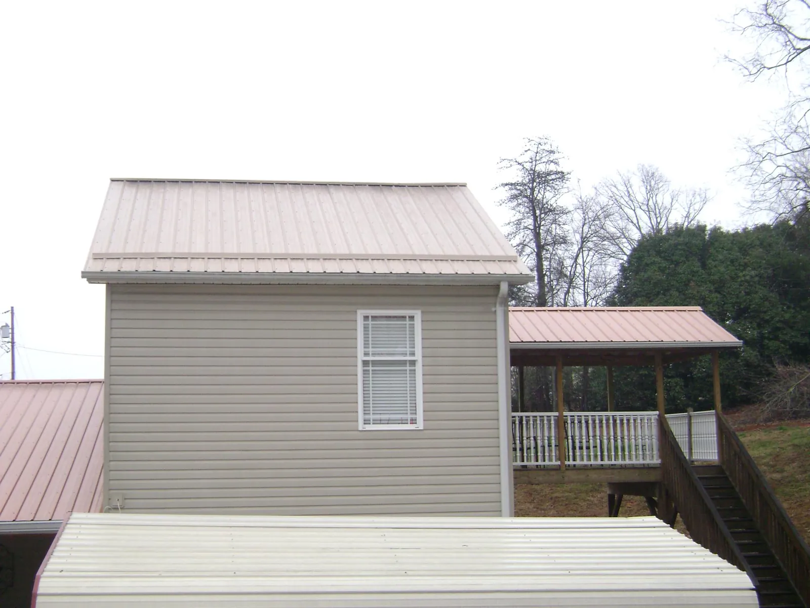 Tan metal roofs on a two story addition and attached porch, from a Roof Replacement job in Fairmount