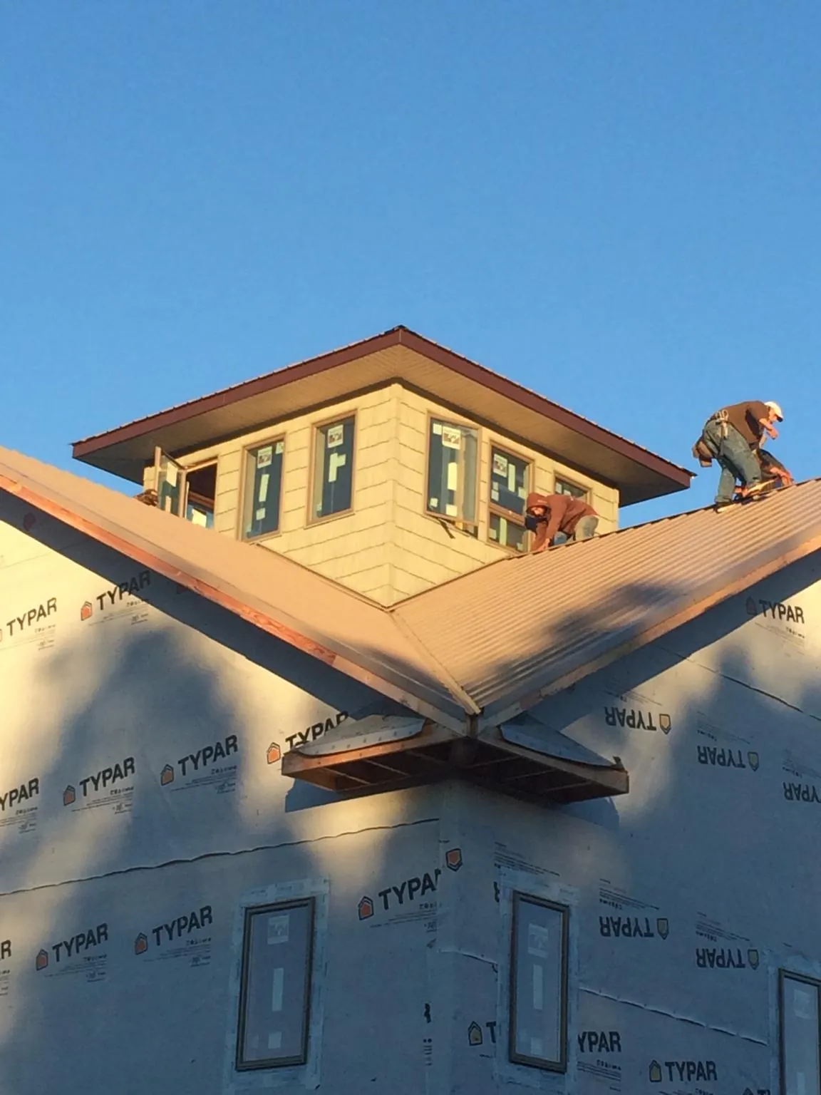 Roofers working around a rooftop cupola on a new metal roof at sunset — Roof Waterproofing in Fairmount by Roofing Brothers